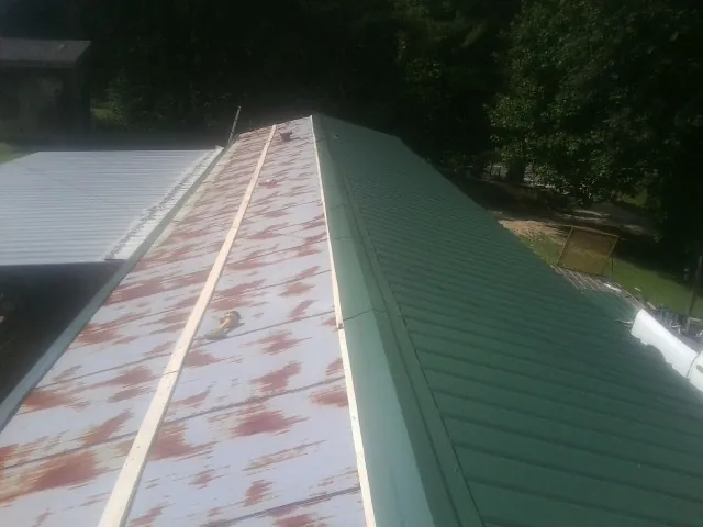 Old rusted panels beside newly installed green metal roofing — Wind Damage Roof Repair by Roofing Brothers in Olney