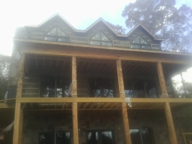Dormers and porch framing on a large log home under construction — Roof Coating work by our crew in Olney