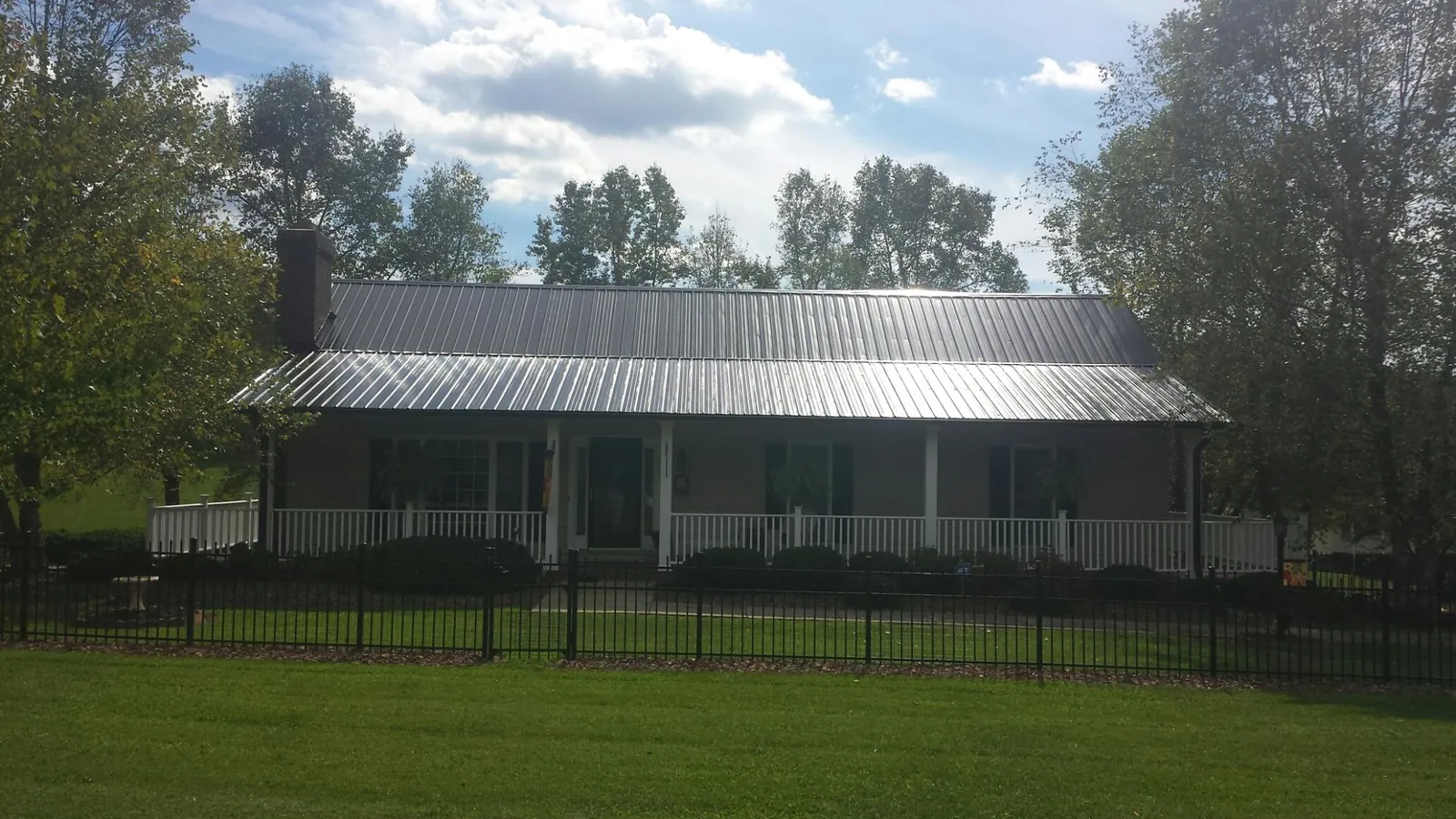 Gray metal roof on a brick ranch with a full width front porch — Gutter Guard Installation work by our crew in Olney