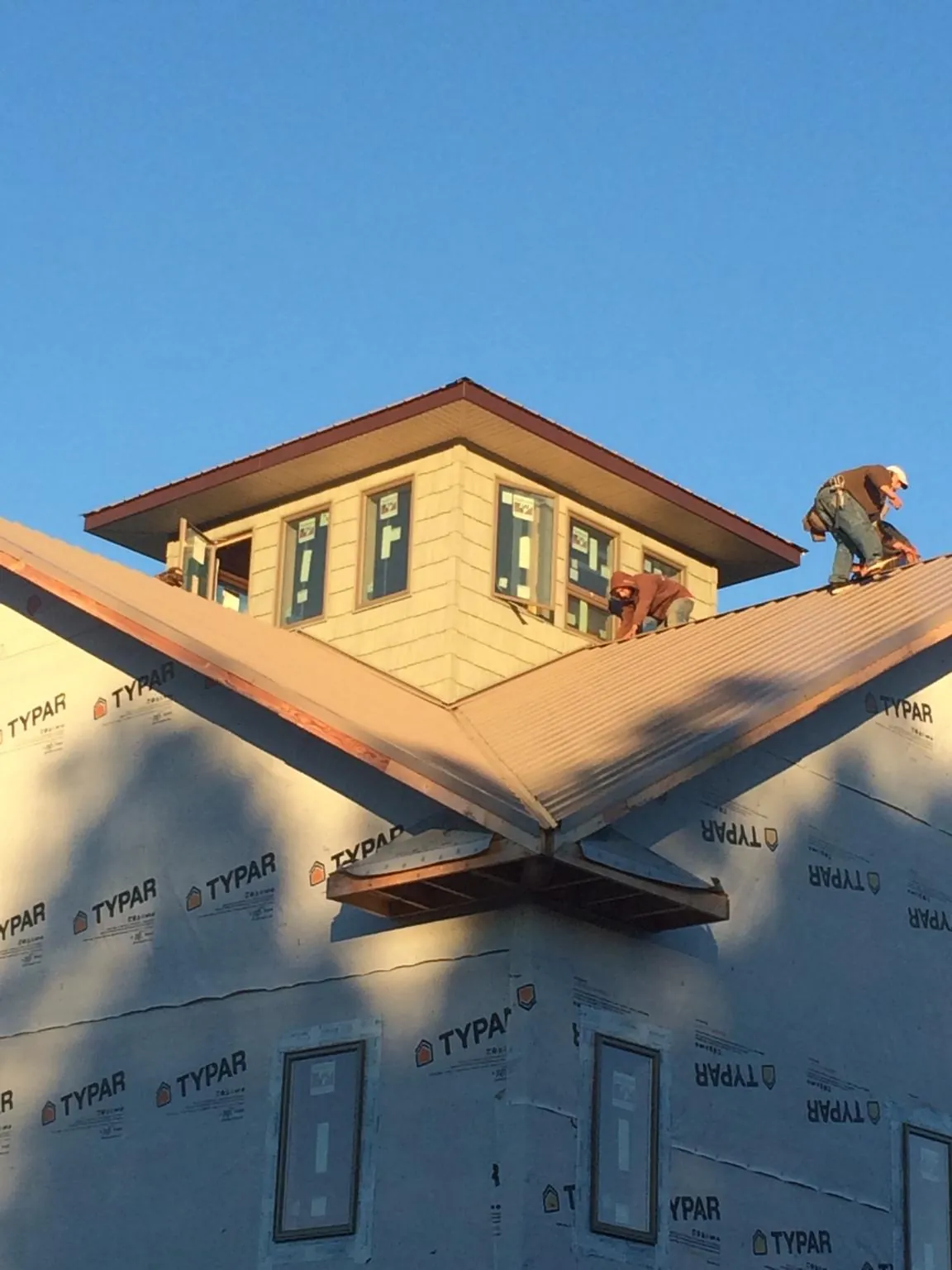 Roofers working around a rooftop cupola on a new metal roof at sunset — Roof Waterproofing in Olney by Roofing Brothers